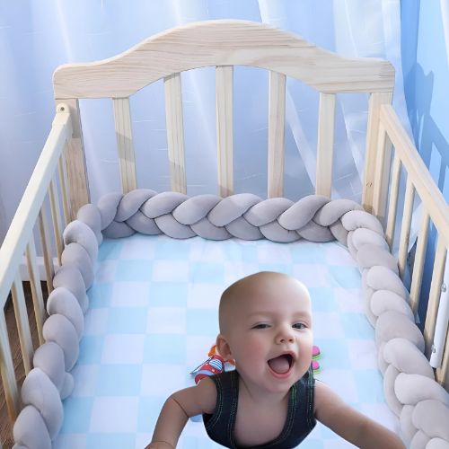 Bébé joue dans son lit à barreau sécurisé avec une tresse de lit bebe grise