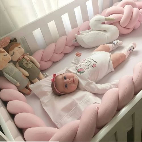 Petite fille allongée tranquillement d'un berceau entouré de la tresse de lit bébé rose gold