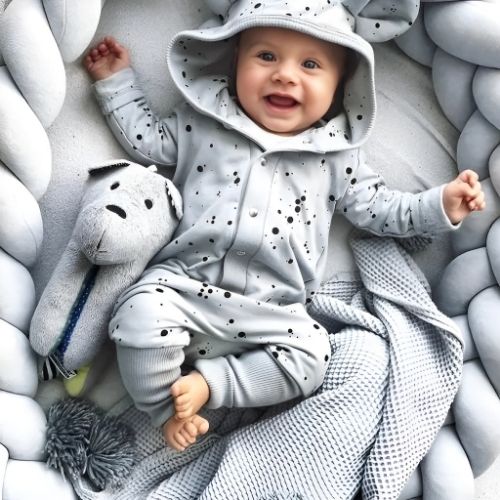 Bébé heureux dans son cocon sécurisant entourer de la tresse de lit bebe grise facile à transporter partout