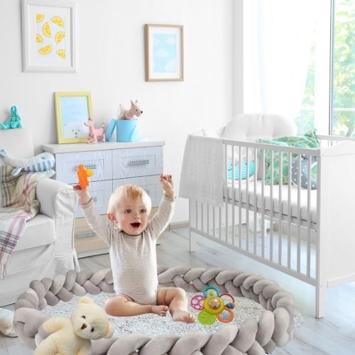 Bébé joue sur un tapis de jeux sécurisé par une tresse de lit bebe grise