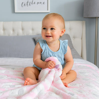 Bébé fille tiens la couverture bébé rose douce entre ses mains